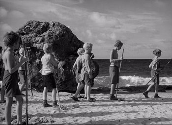 Movie still from “Lord of the Flies” (1963), directed by Peter Brook – A black and white photo of a group of people on the beach; Wide shot, High angle