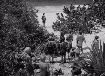 Movie still from “Lord of the Flies” (1963), directed by Peter Brook – A group of people standing on top of a sandy beach; Extreme Wide shot, High angle