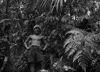 Movie still from “Lord of the Flies” (1963), directed by Peter Brook – Black and white photograph of a young man standing in the jungle; Wide shot, Low angle