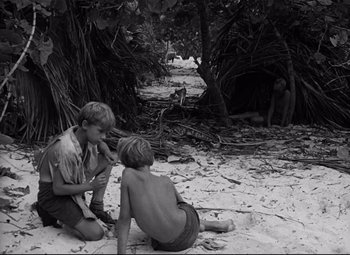 Movie still from “Lord of the Flies” (1963), directed by Peter Brook – Two boys sitting on the ground in the sand; Wide shot, High angle