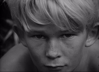 Movie still from “Lord of the Flies” (1963), directed by Peter Brook – Black and white photograph of a young man with a sad look; Close Up shot, High angle