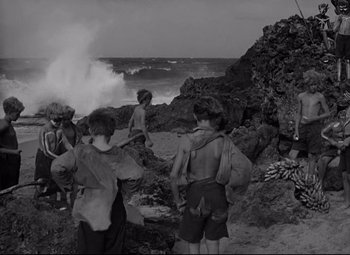 Movie still from “Lord of the Flies” (1963), directed by Peter Brook – A black and white photo of a group of people on the beach; Wide shot, High angle