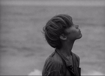 Movie still from “Lord of the Flies” (1963), directed by Peter Brook – A young man standing in front of a body of water; Close Up shot, Over the shoulder angle