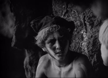 Movie still from “Lord of the Flies” (1963), directed by Peter Brook – A man with a hat on his head and a bare torso; Close Up shot, High angle