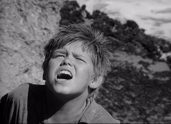 Movie still from “Lord of the Flies” (1963), directed by Peter Brook – A young boy with his mouth wide open and his head tilted to the side; Close Up shot, Low angle