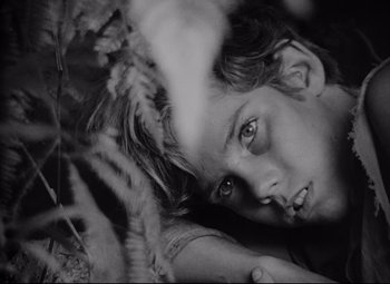 Movie still from “Lord of the Flies” (1963), directed by Peter Brook – A young boy laying on the ground looking at the camera; Close Up shot, High angle
