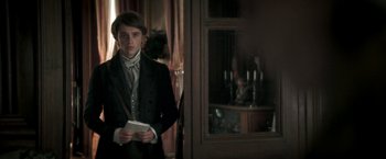 Movie still from “Lost Illusions” (2021), directed by Xavier Giannoli – A young man in a suit holding a book in his hands; Medium shot, Over the shoulder angle