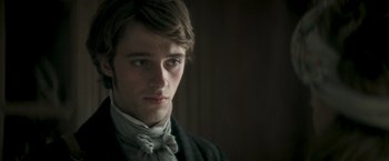 Movie still from “Lost Illusions” (2021), directed by Xavier Giannoli – A young man wearing a suit and bow tie looking at the camera; Close Up shot, Over the shoulder angle