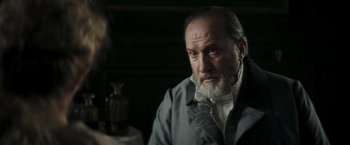 Movie still from “Lost Illusions” (2021), directed by Xavier Giannoli – An older man sitting in front of a table; Close Up shot, Over the shoulder angle