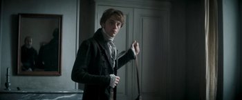 Movie still from “Lost Illusions” (2021), directed by Xavier Giannoli – A young man holding a cane in a room; Medium shot, Over the shoulder angle