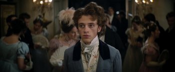 Movie still from “Lost Illusions” (2021), directed by Xavier Giannoli – A young man in a suit and tie standing in front of a crowd; Close Up shot, Over the shoulder angle