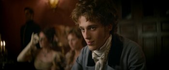 Movie still from “Lost Illusions” (2021), directed by Xavier Giannoli – A young man in a blue jacket and a white neck tie; Close Up shot, Over the shoulder angle