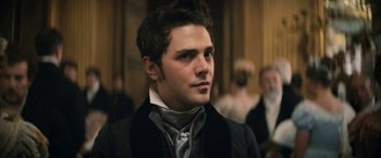 Movie still from “Lost Illusions” (2021), directed by Xavier Giannoli – A man in a black jacket and a gray tie; Close Up shot, Over the shoulder angle