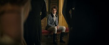 Movie still from “Lost Illusions” (2021), directed by Xavier Giannoli – A man sitting on top of a bench in a room; Medium shot, Over the shoulder angle