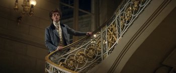 Movie still from “Lost Illusions” (2021), directed by Xavier Giannoli – A man in a suit standing on top of a staircase; Medium shot, Low angle