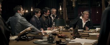 Movie still from “Lost Illusions” (2021), directed by Xavier Giannoli – A group of people sitting around a table; Medium shot, High angle