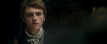 Movie still from “Lost Illusions” (2021), directed by Xavier Giannoli – A young man wearing a neck tie and a suit; Close Up shot, Over the shoulder angle