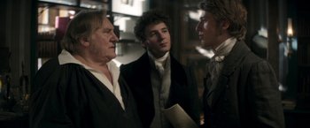 Movie still from “Lost Illusions” (2021), directed by Xavier Giannoli – A group of men standing next to each other in a room; Medium shot, Over the shoulder angle