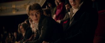 Movie still from “Lost Illusions” (2021), directed by Xavier Giannoli – A man sitting in front of a group of people; Medium shot, Over the shoulder angle
