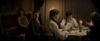 Movie still from “Lost Illusions” (2021), directed by Xavier Giannoli – A group of people sitting around a table; Medium shot, Over the shoulder angle