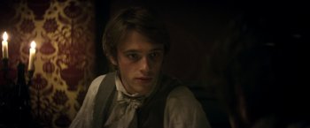 Movie still from “Lost Illusions” (2021), directed by Xavier Giannoli – A man in a vest and bow tie looking at the camera; Close Up shot, Over the shoulder angle