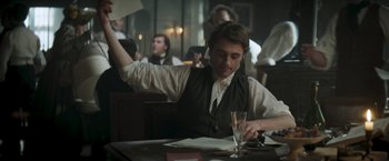 Movie still from “Lost Illusions” (2021), directed by Xavier Giannoli – A man sitting at a table with papers and a glass of wine; Medium shot, Low angle