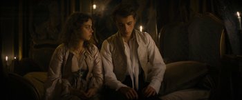 Movie still from “Lost Illusions” (2021), directed by Xavier Giannoli – A man and a woman sitting next to each other in front of candles; Medium shot, Low angle