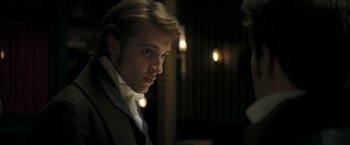 Movie still from “Lost Illusions” (2021), directed by Xavier Giannoli – A man in a suit and tie looking at the camera; Close Up shot, Over the shoulder angle