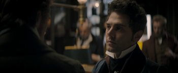 Movie still from “Lost Illusions” (2021), directed by Xavier Giannoli – A man in a suit and tie looking to his left; Close Up shot, Over the shoulder angle