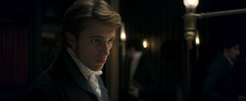 Movie still from “Lost Illusions” (2021), directed by Xavier Giannoli – A man in a suit and tie looking at the camera; Close Up shot, Over the shoulder angle