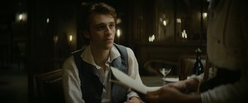 Movie still from “Lost Illusions” (2021), directed by Xavier Giannoli – A man sitting at a table with a paper in front of him; Close Up shot, Over the shoulder angle