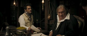 Movie still from “Lost Illusions” (2021), directed by Xavier Giannoli – Two men sitting at a table with papers in front of them; Medium shot, Over the shoulder angle