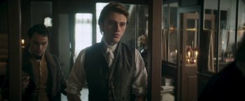 Movie still from “Lost Illusions” (2021), directed by Xavier Giannoli – A man in a vest and tie standing in a room; Medium shot, Over the shoulder angle