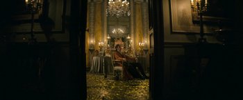 Movie still from “Lost Illusions” (2021), directed by Xavier Giannoli – A man sitting on a chair in a room with a chandelier; Wide shot, Low angle