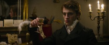 Movie still from “Lost Illusions” (2021), directed by Xavier Giannoli – A young man holding a glass of wine; Close Up shot, Low angle
