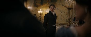 Movie still from “Lost Illusions” (2021), directed by Xavier Giannoli – A woman in a black coat standing in front of a wall with candles; Medium shot, Over the shoulder angle