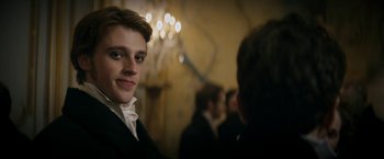 Movie still from “Lost Illusions” (2021), directed by Xavier Giannoli – A young man in a tuxedo smiling at the camera; Close Up shot, Over the shoulder angle