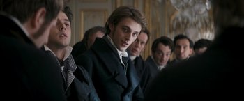 Movie still from “Lost Illusions” (2021), directed by Xavier Giannoli – A group of men standing next to each other in front of a wall; Close Up shot, Over the shoulder angle