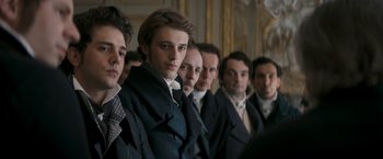 Movie still from “Lost Illusions” (2021), directed by Xavier Giannoli – A group of men standing next to each other in a room; Medium shot, Over the shoulder angle