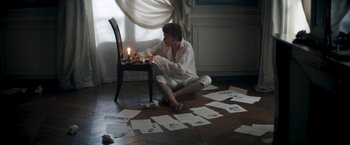 Movie still from “Lost Illusions” (2021), directed by Xavier Giannoli – A man sitting on the floor with a lit candle in front of him; Wide shot, High angle