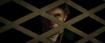 Movie still from “Lost Illusions” (2021), directed by Xavier Giannoli – A young man looking through a wooden lattice; Close Up shot, Over the shoulder angle