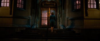 A woman standing on steps looking out of a window