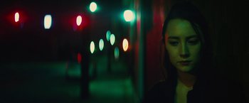 A woman standing next to a wall at night