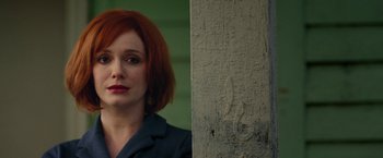 A woman with red hair standing in front of a wall