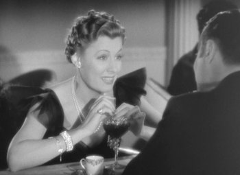 Movie still from “Love Affair” (1939), directed by Leo McCarey – A woman sitting at a table with a glass of red wine; Close Up shot, Over the shoulder angle