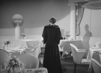 Movie still from “Love Affair” (1939), directed by Leo McCarey – A woman standing in front of a table in a restaurant; Wide shot, Low angle