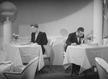 Movie still from “Love Affair” (1939), directed by Leo McCarey – A man and a woman sitting at a table in front of each other; Wide shot, High angle