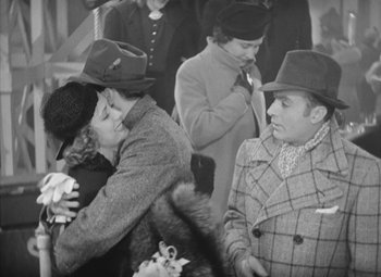 Movie still from “Love Affair” (1939), directed by Leo McCarey – A man and a woman hugging in a crowd of people; Medium shot, Over the shoulder angle
