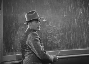Movie still from “Love Affair” (1939), directed by Leo McCarey – A black and white photo of a man wearing a hat; Medium shot, High angle