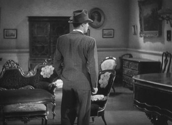Movie still from “Love Affair” (1939), directed by Leo McCarey – A black and white photo of a man in a suit and hat; Wide shot, High angle